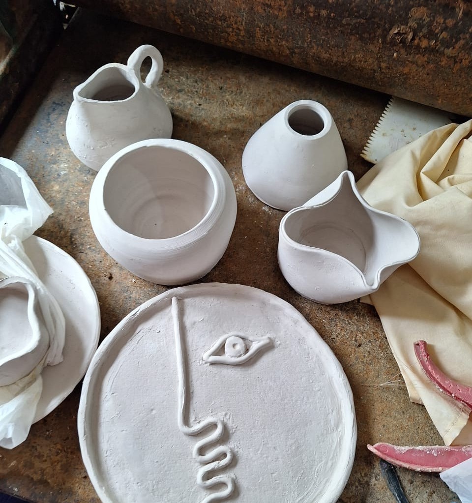Glazed ceramic face plate surrounded by handmade vessels