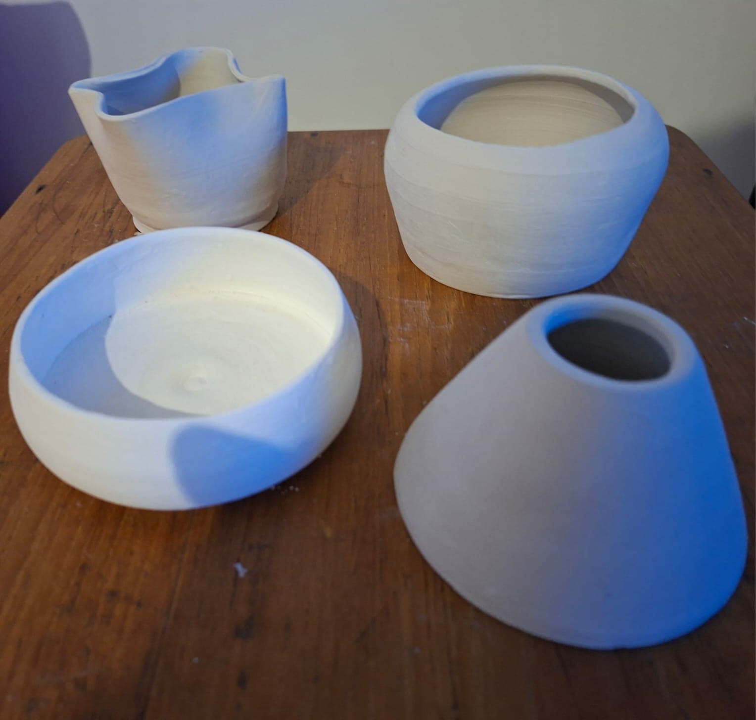 Four finished ceramic pieces resting on the workshop table