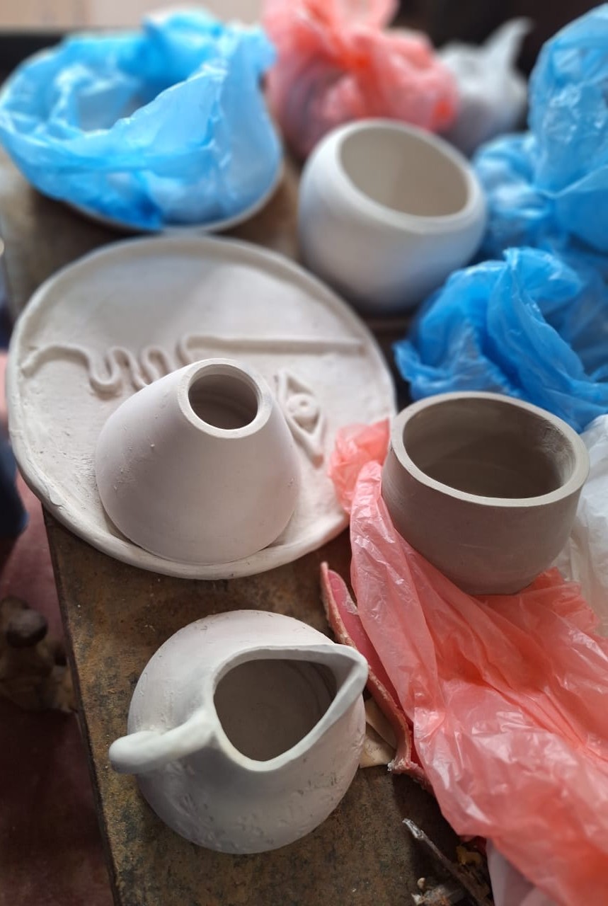 Ceramic greenware kept under plastic wrap to dry slowly
