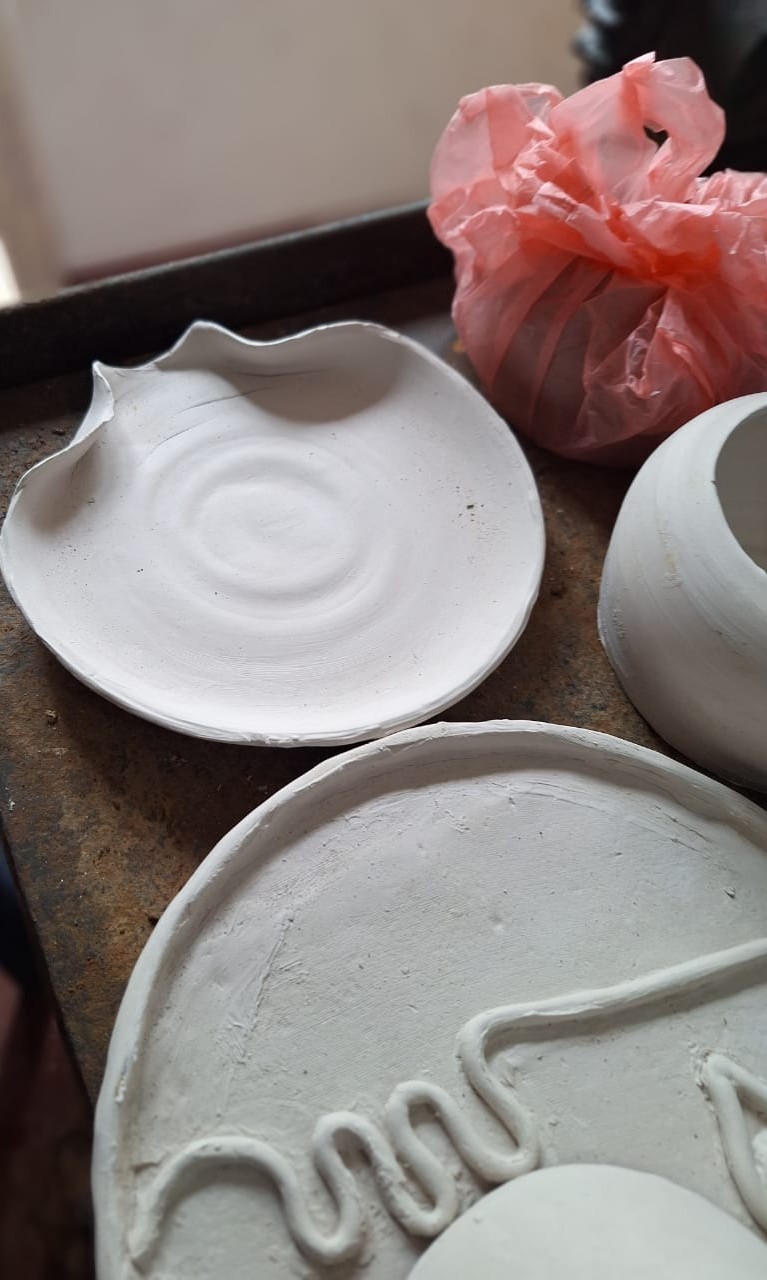 Handmade ceramic plates lined up and drying on the workbench