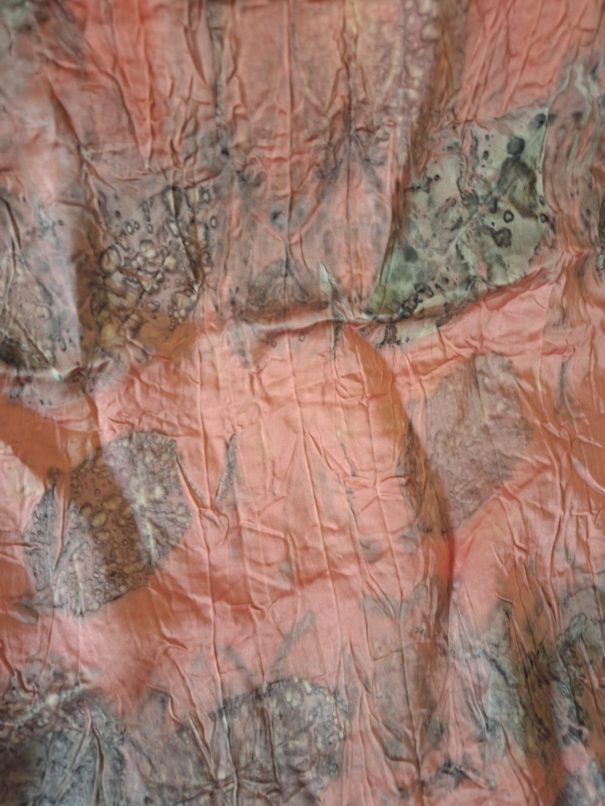 Coral dyed cloth carrying the ghostly prints of leaves