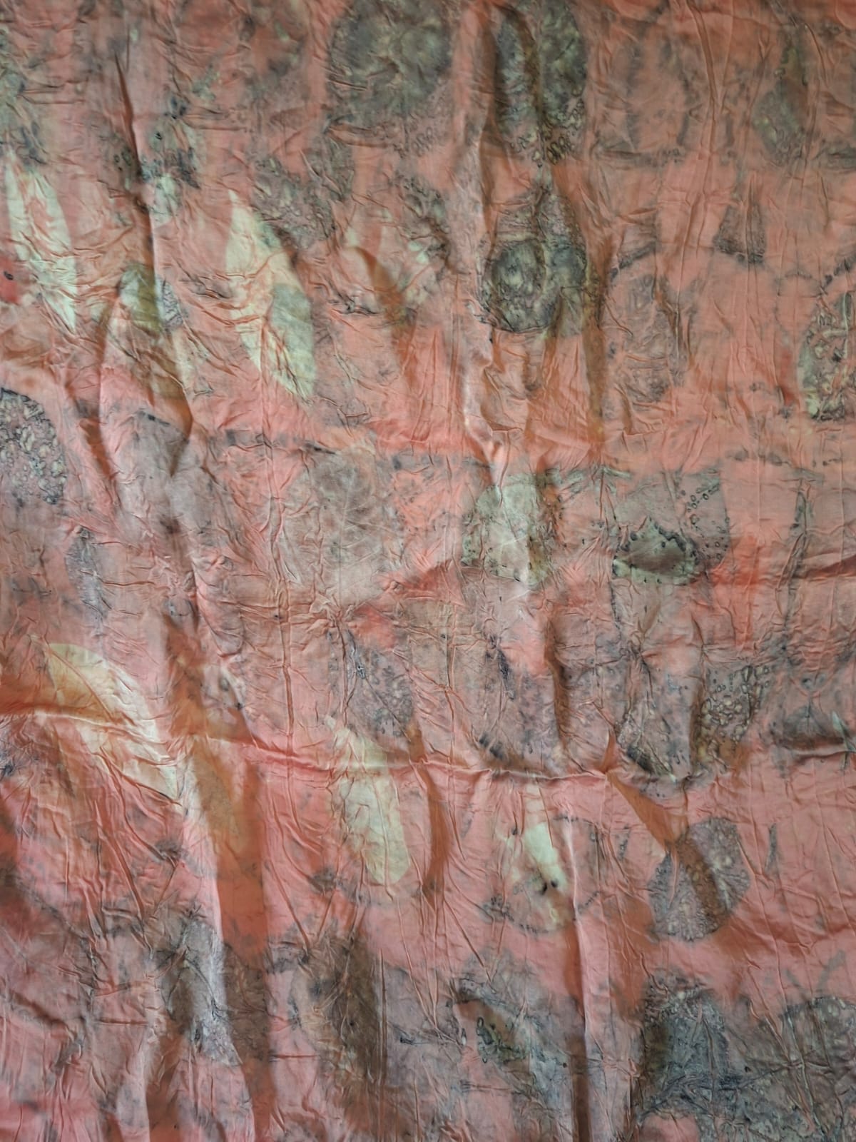 A length of coral eco printed cloth patterned with pale leaf shapes