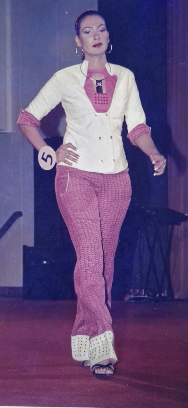 A model on stage in a cream jacket and textured pink trousers