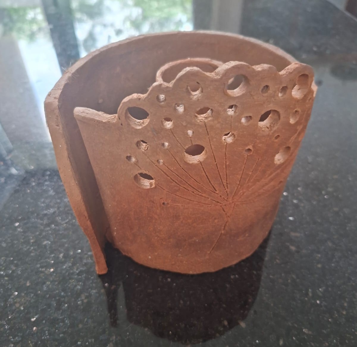 Side view of a red clay dandelion pot showing the pierced details