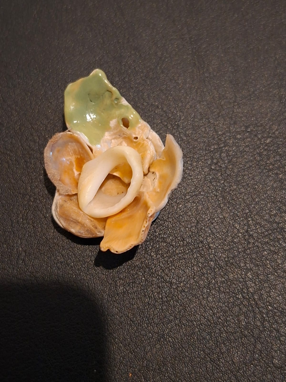 A brooch of overlapping shells glazed in cream and soft green
