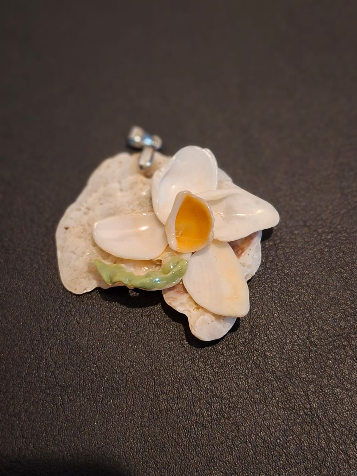 A blossom of white shells set on a piece of coral, with a silver bail