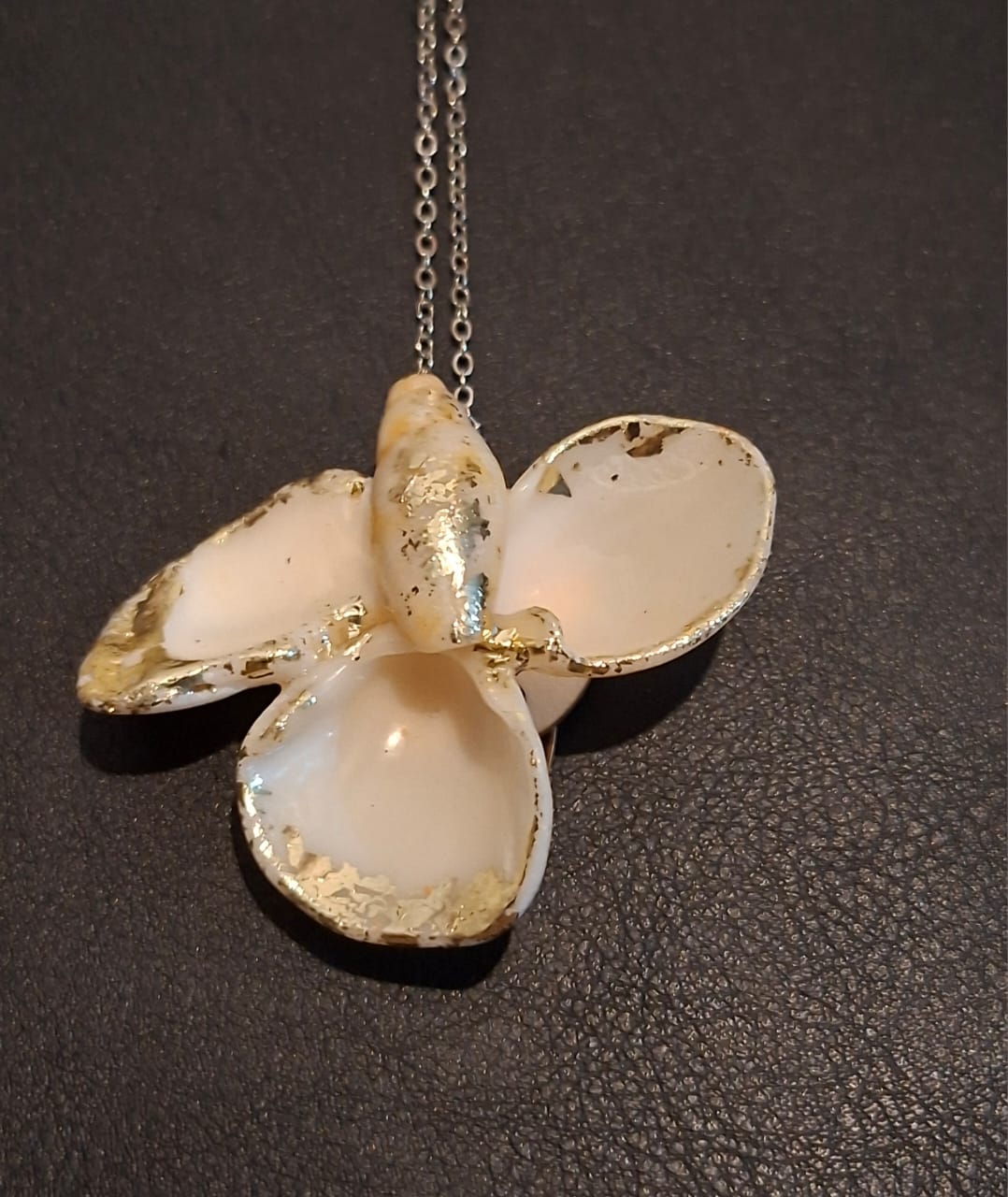 A three petalled ivory shell pendant with gold leaf, on a fine silver chain