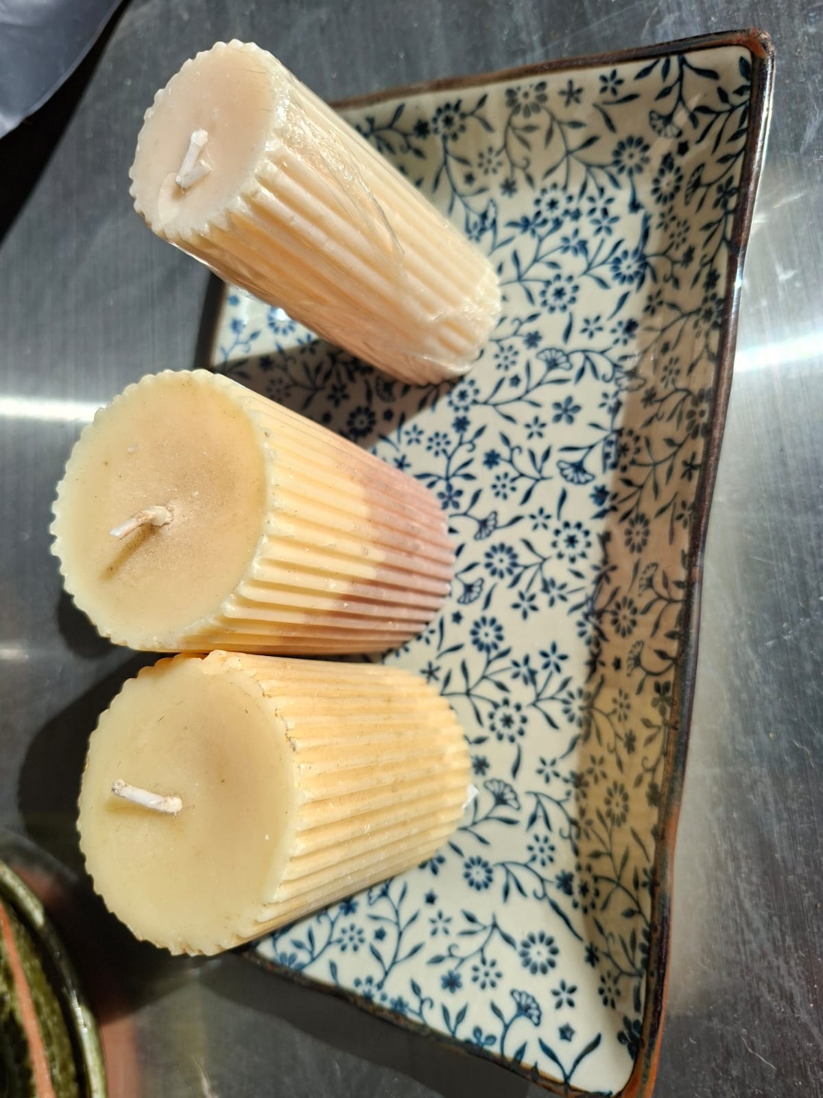 Fluted beeswax pillar candles resting on a blue floral ceramic tray