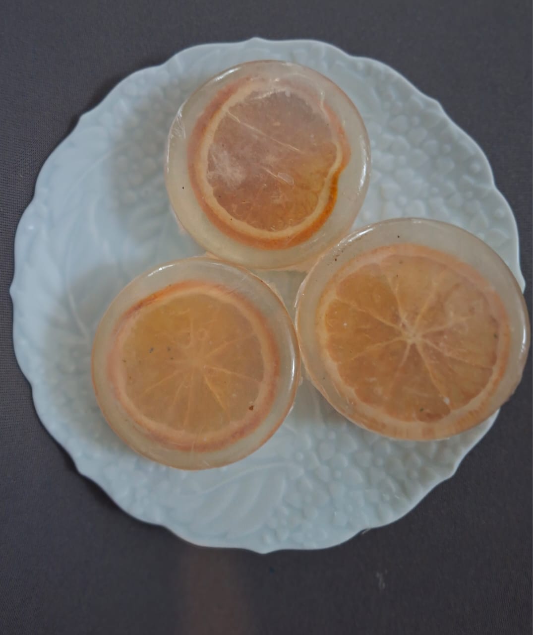 Translucent soaps set with dried citrus slices on a white plate