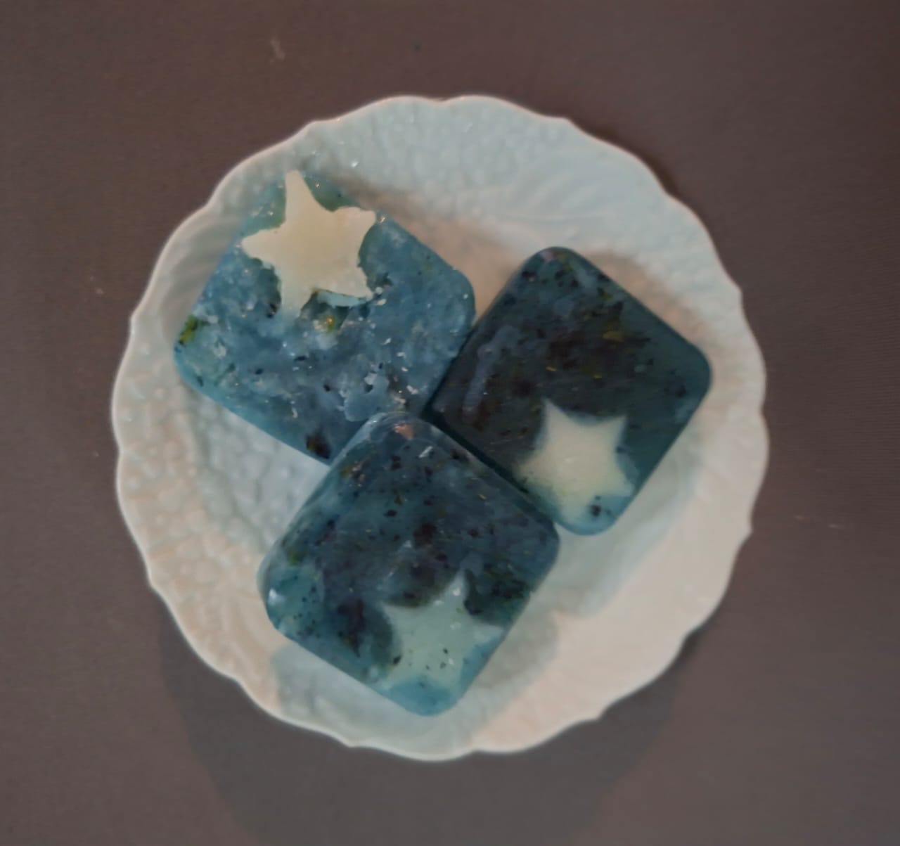 Deep blue soaps with pale stars set into them, on a white plate
