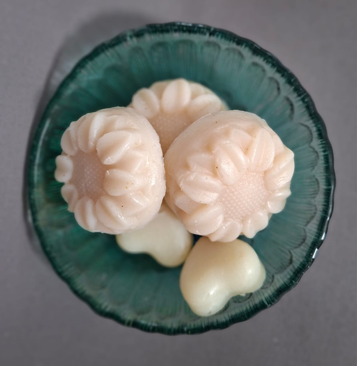 Sunflower moulded soaps resting in a teal fluted bowl